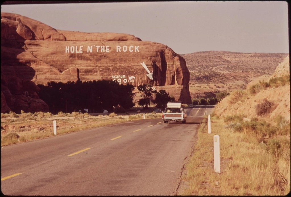 Roadside curio shop sign painted on a rock beside a North American desert highway in 1972.